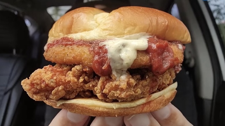 Hands holding a DIY chicken parm sandwich dripping with marinara sauce