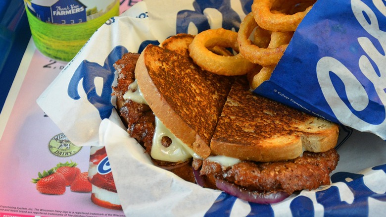 A patty melt sandwich and onion rings on tray at Culver's restaurant.