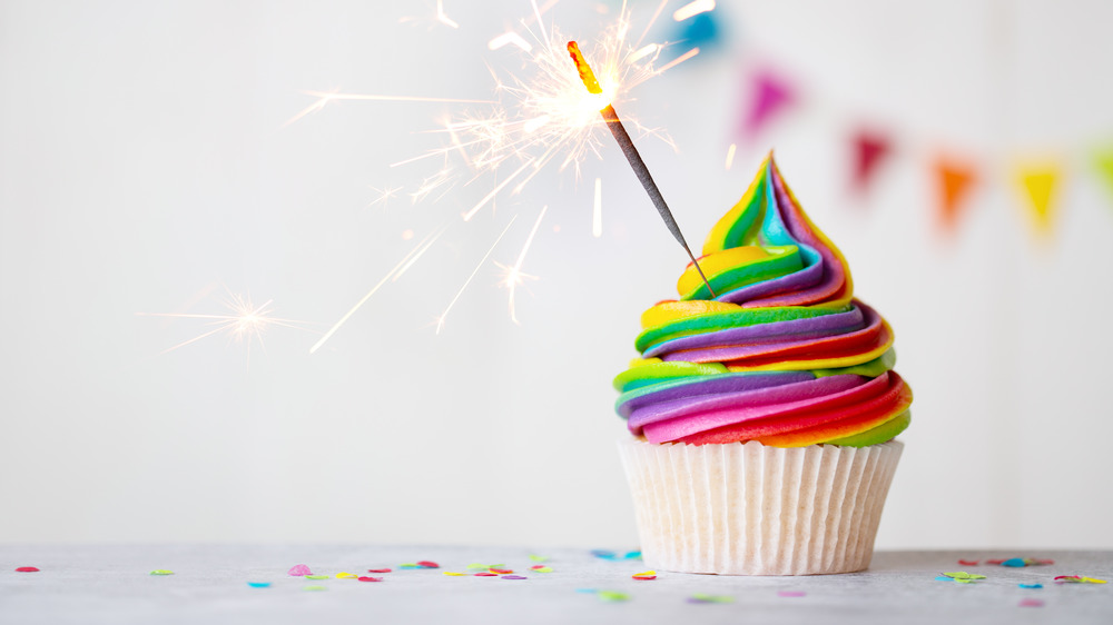 vanilla cupcake with tie-dyed frosting and a sparkler