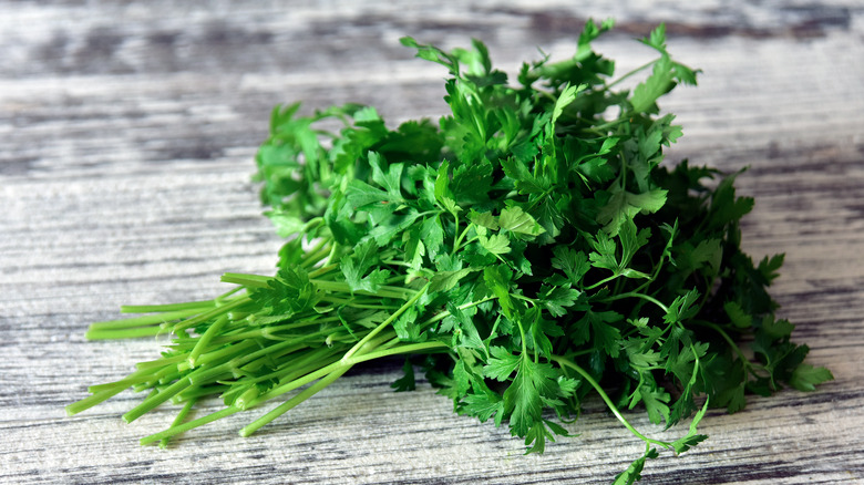 woman grabbing parsley in the produce section of the grocery store 