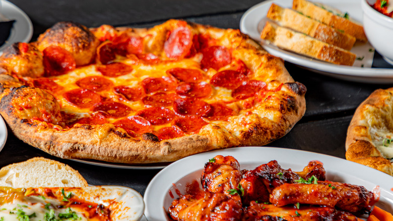 pepperoni pizza with surrounding side dishes