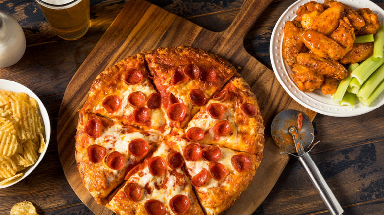 Pepperoni pizza with chicken wings and potato chips