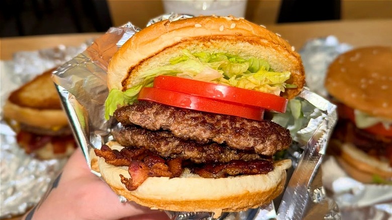 Double patty burger with tomato and lettuce with bacon on toasted bun from Five Guys