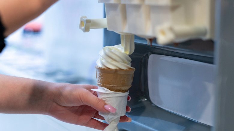Person making a vanilla ice cream cone at a fast food restaurant.