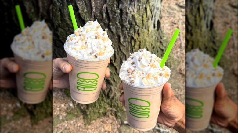 Two people holding two s'mores milkshakes from Shake Shack.