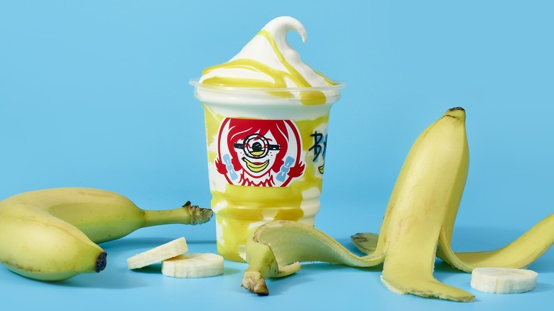 A banana-flavored Frosty Swirl from Wendy's with peeled and unpeeled bananas surrounding it.