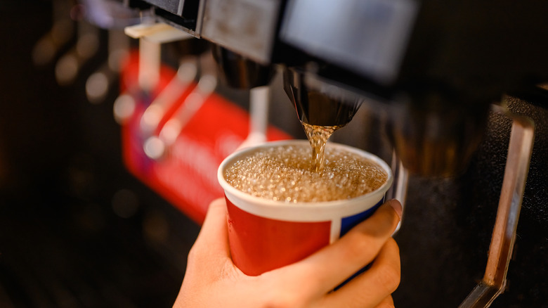 Soda machine dispensing fizzy beverage in restaurant.