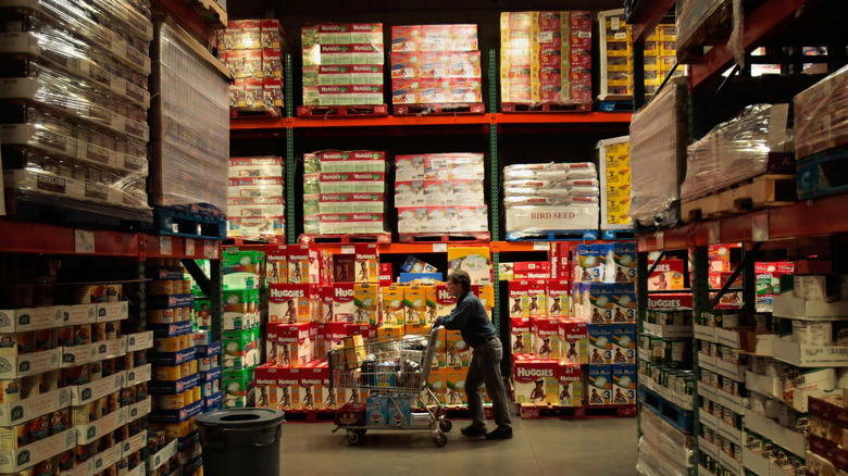Shopper pushing cart through Costco aisle.