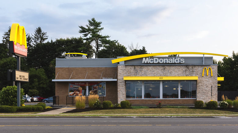 McDonald's restaurant with roadside sign, and cars parked in the lot to the left.