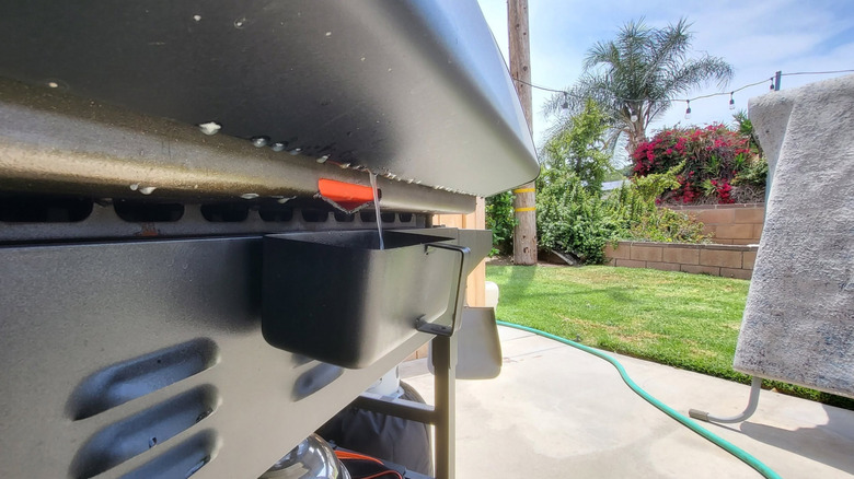 Closeup of the grease trap on the back of a Blackstone grill in a backyard