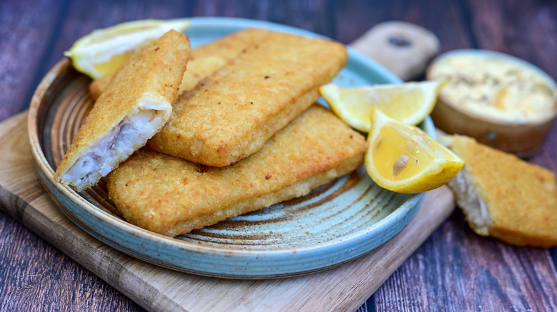 Filets of crispy fried Alaska pollock fish with lemon wedges
