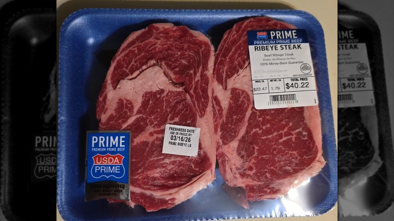 Two pieces of USDA Prime ribeye steaks from Walmart, in a blue plastic tray, and wrapped with clear plastic.
