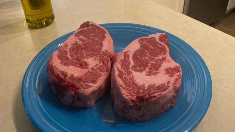 Two USDA Prime ribeye steaks in a blue plate from Whole Foods