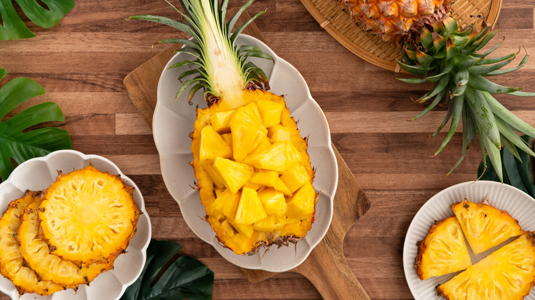 Cubed pineapple in hull on white platter.