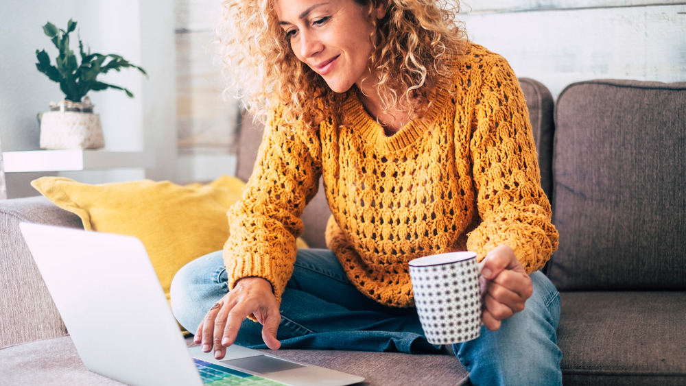 Person shopping on laptop with a coffee mug in hand