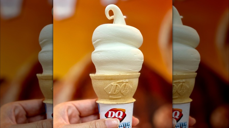 Hand holding DQ vanilla soft serve cone with curly top