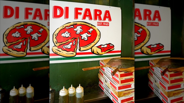 Di Fara sign with a stack of pizza boxes and pizza paddles
