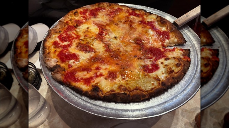 Cheese pizza on a stainless steel pizza pan