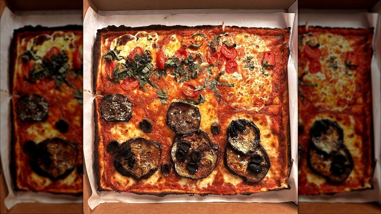 Square pizza in a box, half with mushroom toppings and the other half topped with cheese, tomatoes, and basil