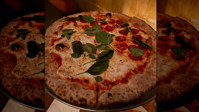 Coal-fired half-cheese, half-pepperoni pizza topped with basil
