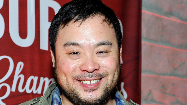 David Chang smiling in front of red flag