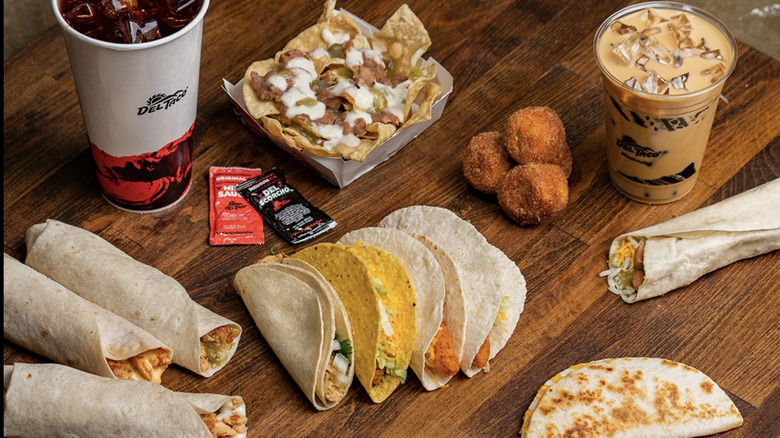 tacos and burritos with iced coffee and donuts on a wooden table