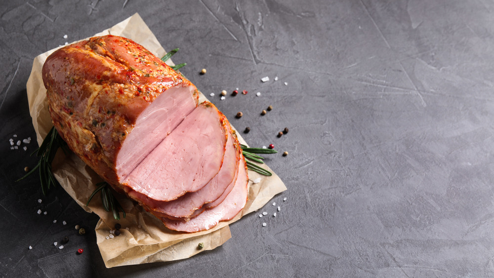 Sliced ham on gray table with spices
