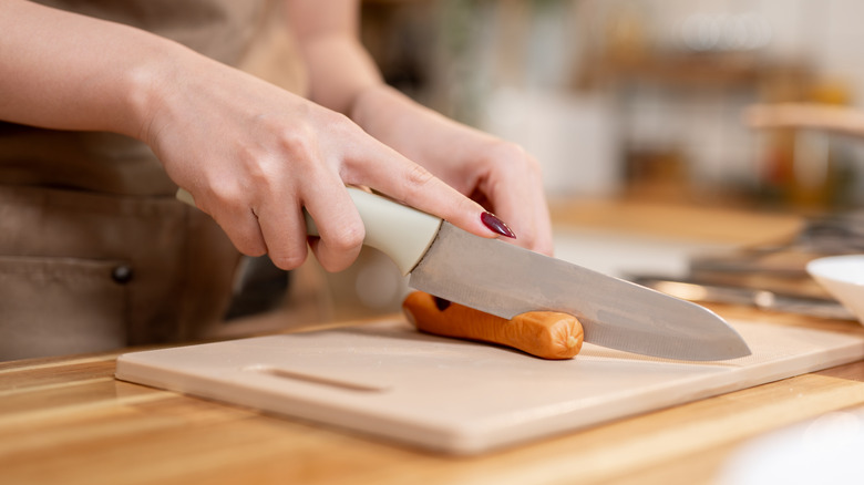Chopping up hot dog with knife
