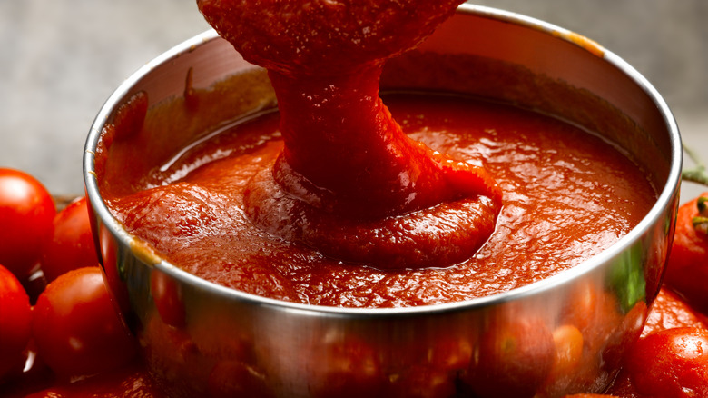 A big pot of tomato sauce on top of fresh tomatoes