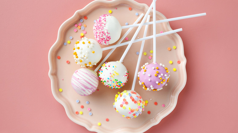 Various cake pops on pink surface