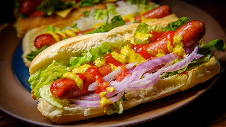 Natural casing hot dogs with ketchup, mustard, lettuce, and onions