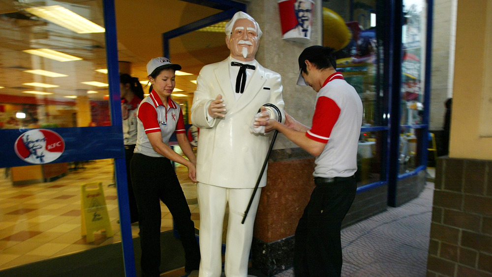 Workers carrying a statue of Colonel Sanders