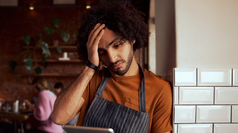 Waiter looking seriously at tablet