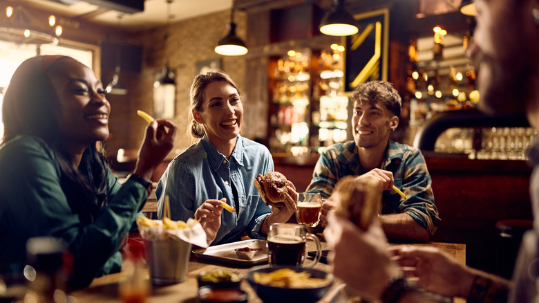 People socializing, eating fries, and drinking at a pub