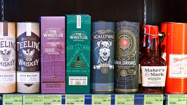 Bottles of single malt and blended whiskeys with their prices on a store shelf