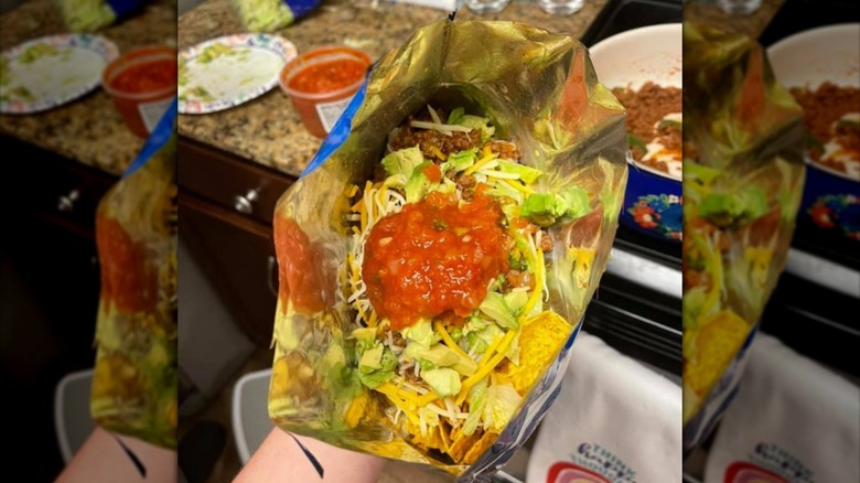 Hand holding walking taco in home kitchen.