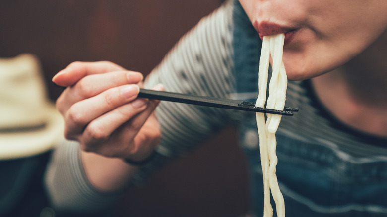 using chopsticks to eat noodles