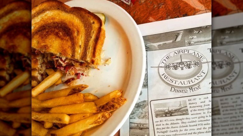 Reuben sandwich and fries next to dinner menu for The Airplane Restaurant