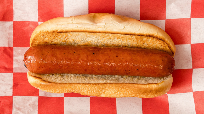 Plain hot dog in a bun on checkered paper