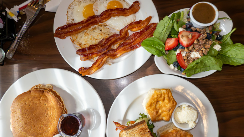 Spread of diner food, including eggs, bacon, pancakes, and salad
