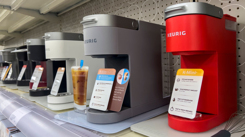 Row of red, gray, white, and black Keurig coffee makers
