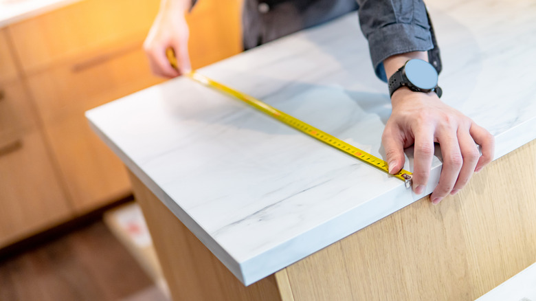 Measuring granite countertop with measuring tape