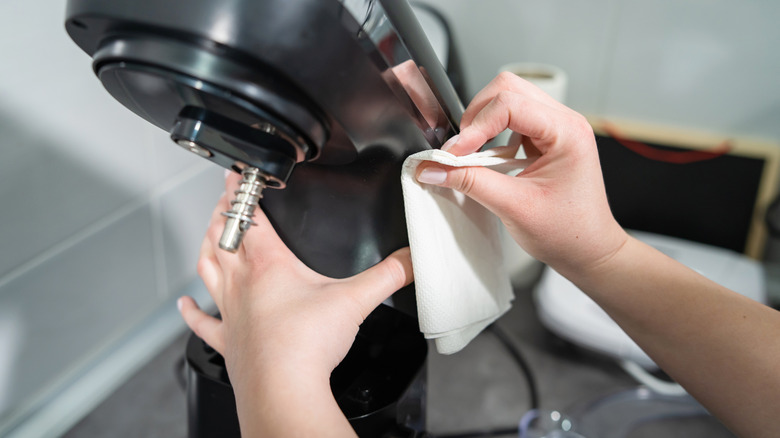Person delicately wiping tilt-head of black stand mixer
