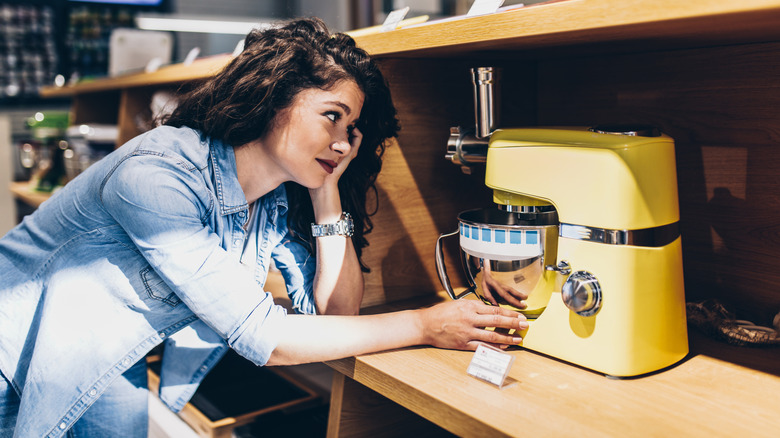 Customer looking at and touching yellow stand mixer in store