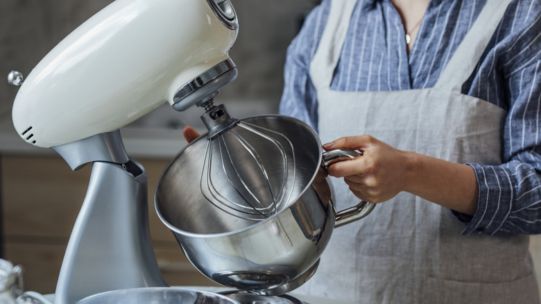Person removing large metal bowl from stand mixer