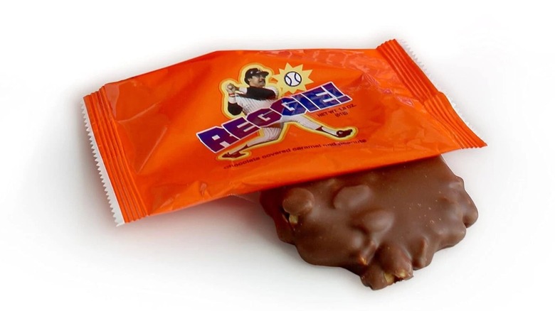 A close-up of a round, textured chocolate candy bar in orange packaging with the name Reggie! on it