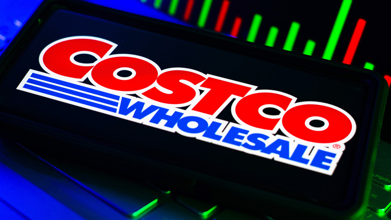Costco Wholesale logo on a smartphone on top of a keyboard with colored bars in the background