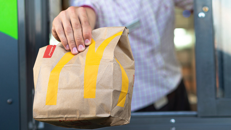 Person at McDonald's serving drive thru bag of food