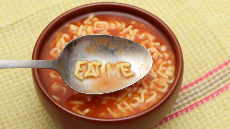 alphabet pasta spelling Eat Me in bowl with spoon