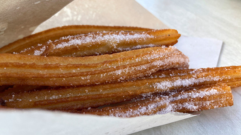 A bunch of churros wrapped in paper sit on a table.